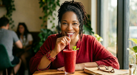Woman enjoying a red smoothie in a casual indoor setting